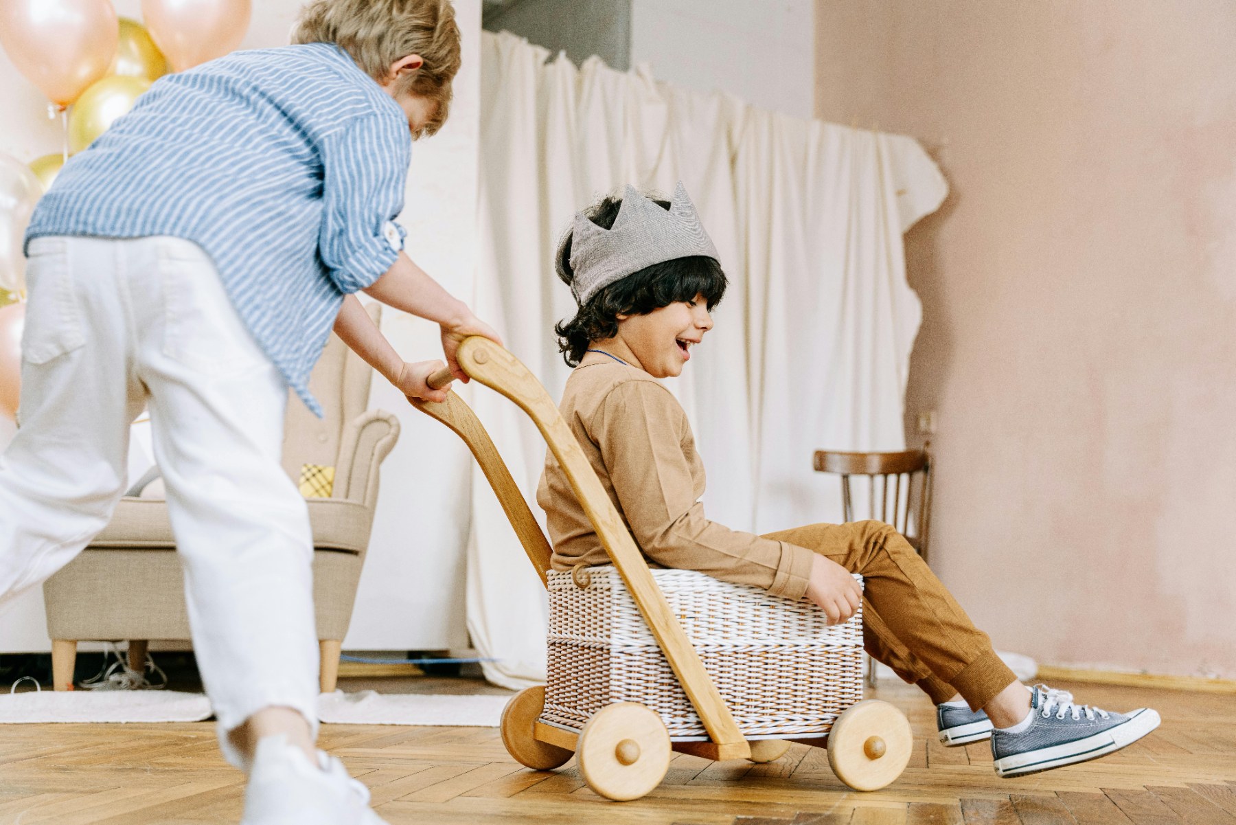 Two children playing with a wooden push-wagon at a party